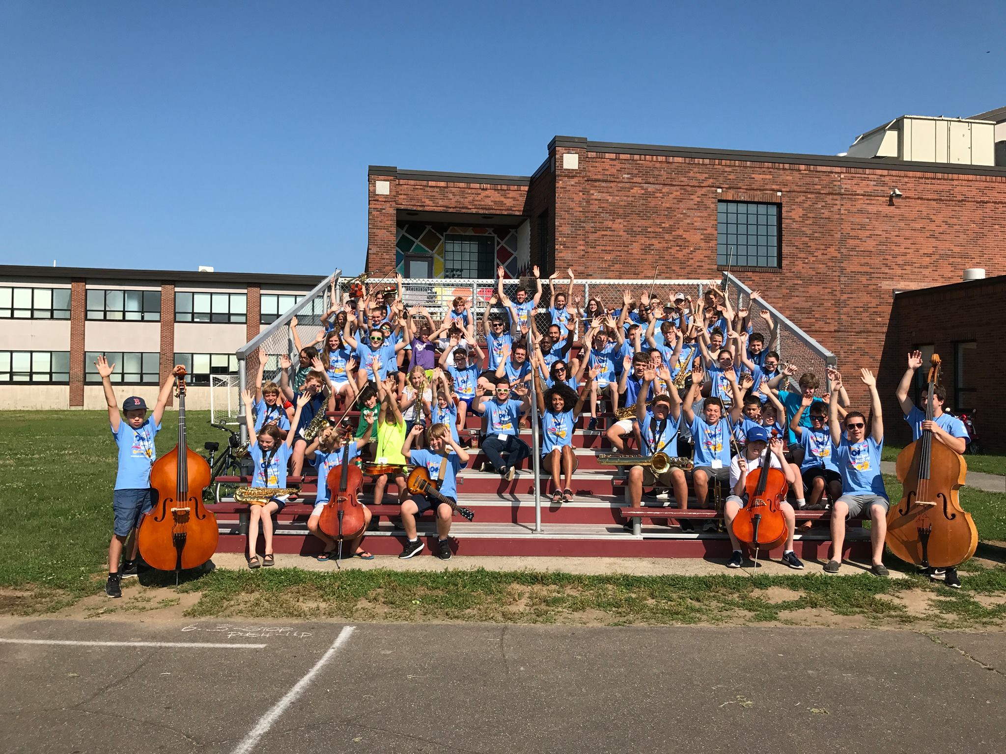 Rockport Jazz Workshop music students with musical instruments smiling and raising their hands